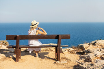 Sticker - Lonely woman sitting on a bench and looks at the lagoon. Summer vacation holiday.