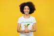 © ViDi Studio - Young woman of African American ethnicity wears white volunteer t-shirt hold in hands little plant sprout isolated on plain yellow background Voluntary free work assistance help charity grace concept