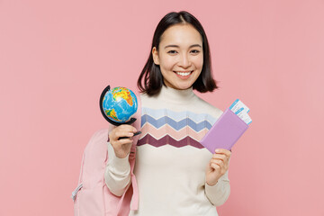 Wall Mural - Traveler tourist student girl of Asian ethnicity wear sweater hold passport tickets globe isolated on plain pastel pink background. Passenger travel abroad weekends getaway Air flight journey concept