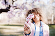 © Eva - happy hispanic woman with afro hair in spring among pink blossom flowers. selective focus on flowers