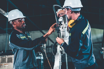 Factory workers working with adept robotic arm in a workshop . Industry robot programming software for automated manufacturing technology .