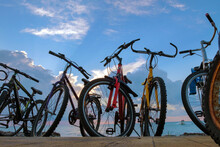 The Row Of Bikes On The Beach Wit Blue Cloudy Sky Background