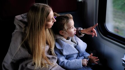 Wall Mural - Mom and daughter ride in a train near the window