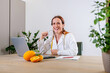 Portrait of smiling young female nutritionist in her office in medical gown with fresh oranges. Dietologist making a diet plan
