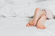 © Evgenii - Childs legs are covered with white bed linen. The warmth of home comfort.
