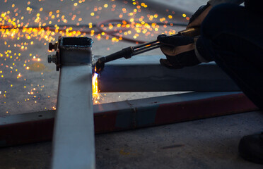 Wall Mural -  steel with acetylene torch in factory. Workers wearing industrial uniforms and welding masks at a welding factory protect from welding sparks. Occupational safety concept