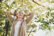 Portrait of happy elderly senior Caucasian woman do stretching and relaxing feel refresh and freedom breathing fresh air with sunlight enjoying a day in the outdoors park on summer