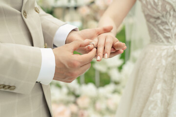 Canvas Print - A married couple exchanges wedding rings at a wedding ceremony. The groom put the ring on the finger of his beautiful wife.