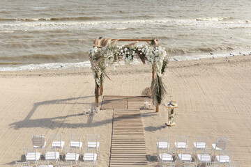 Wall Mural - Outdoor area for beach ceremonies with sea view, white chairs, flower arch on a sunny day