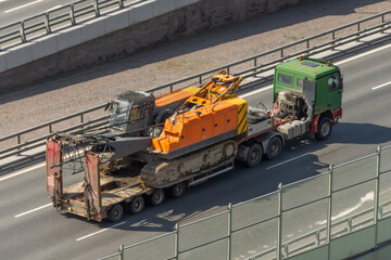 Transportation of a crawler crane on a platform trailer on the road.