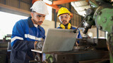 Fototapeta Panele - Two engineers man standing in front of equipment in CNC metal machine factory. Manager looking at tablet and see information how to fix the equipment and explain detail. Discuss and repair