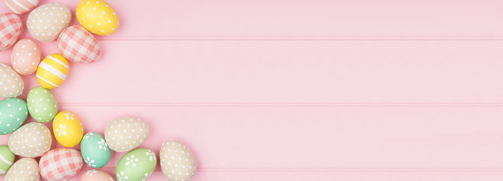 Easter corner border with rustic cloth and pastel colored eggs over a pink wood banner background. Top view with copy space.