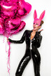© marcink3333 - Sexy blonde woman posing in latex black costume and pink bunny mask and pink balloons on white background. Easter bunny concept. Latex lingerie. Naughty girl. Halloween costume. Woman with balloons.
