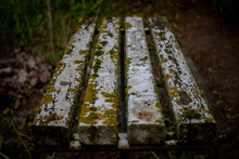 Dirty Old White Painted Bench Overgrown With Moss Found In Latvia Cemetery
