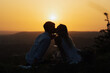 © eduard - Romantic love story. Young couple kissing while sitting at summer picnic on the sunset.