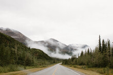 Canada, Yukon, Whitehorse, Empty Road Crossing Hilly Landscape In Fog