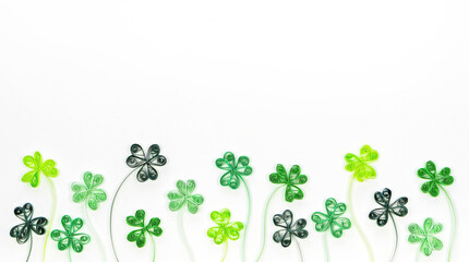 Wall Mural - St. Patrick's Day background with shamrock and trefoil leaves made in paper filigree technique. Quilling paper green clover leaves isolated on white background. Green economic concept banner.
