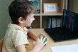 © OlgaKhorkova - 8 years old boy sit by desk with laptop and do exercise with massage ball