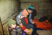 Ukrainian Father With Two Kids Sits In A Bomb Shelter, Waits For The End Of The Air Attack Of Russian Invaders And Reads The Latest Braking News With Smartphone. Terrorism And War, Current History