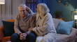 © Andrii Iemelianenko - Senior man sit with wife indoors feels upset, loving woman put hand on shoulders hugs him comforting, express empathy, close-up. Potency health problems, crisis, impotence, incurable disease concept