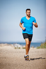 Running keeps me fit. Shot of a handsome young man running on the beach.