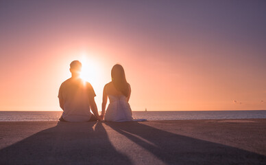 silhouette of couple on beach looking out to the ocean 