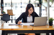 © David - Portrait of Young Asian woman hand freelancer is working her job on computer tablet in modern office. Doing accounting analysis report real estate investment data, Financial and tax systems concept.