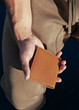 A young man in sportswear is holding a small comfortable red leather purse in his hands. Top view. Vertical orientation, copy space, close-up, no face