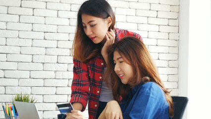 Wall Mural - Happiness two women working together confident team meeting in office desk. Team business partners working with computer laptop startup company. Asian colleague friendship at work with smiling face.