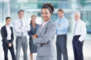 A talented new addition to the team. Happy young African businesswoman standing with her coworkers behind her - portrait.