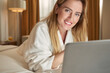 © Viacheslav Yakobchuk - Friendly woman at laptop in bed looking to camera