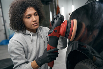 Wall Mural - Skilled service station worker polishing automobile with buffer