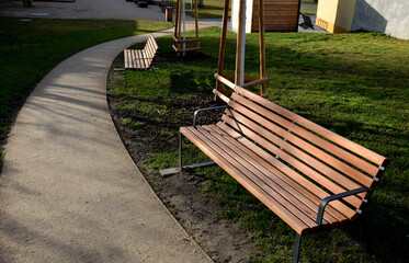 rows of reddish wood benches on their paneling under the benches is a rectangle of concrete anti-scraping beige paths by the shoes of visitors flowering romantic flower beds and lawn