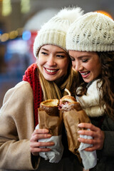 Poster - Happy women friends enjoying christmas market and having fun together outdoors.