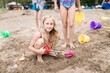 © Westend61 - Girls with beach toys playing in sand at beach
