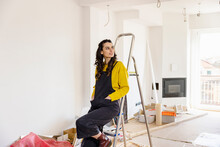Contemplative Woman Sitting On Ladder At New Home
