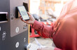 © Westend61 - Woman scanning QR code on ticket machine at station