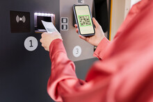 Woman Scanning QR Code On Ticket Machine Through Smart Phone At Station