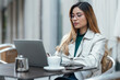 © Westend61 - Freelancer working on laptop sitting at sidewalk cafe