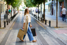Smiling Woman Crossing Road While Carrying Shopping Bag In City