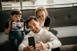 © Westend61 - Happy man taking selfie through smart phone with sons making faces at home