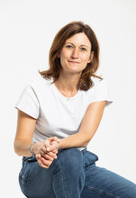 Happy woman sitting against white background at studio