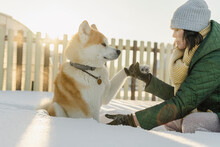 Woman Holding Dog Paw Sitting On Deep Snow In Winter