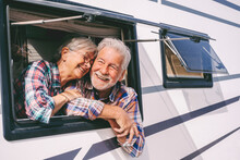 Smiling Senior Woman Leaning On Man Looking Through Window Of Motor Home
