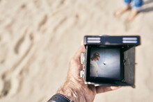 Man Holding Vintage Camera With Woman Picture On It At Beach