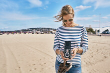 Tourist With Vintage Camera Standing At Beach On Sunny Day