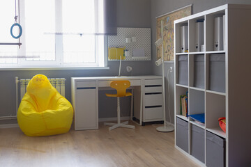 The interior of the room of a boy or girl student in light white and yellow tones, the student's desk in the room at home