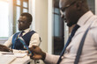 © xartproduction - Two dark-skinned partners of an African American businessman in a meeting work on a laptop in the office. Affordable private courses and distance learning. New opportunities online