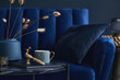 Stylish close up on the elegant details in the glamour living room interior. Golden peacock and creative personal accesories. Dark blue wall. Template. Copy space..