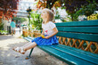 Happy toddler girl sitting on the bench on a street of Paris, France